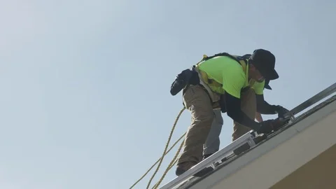 Medium panning low angle shot of workers installing rails on roof / Mapleton, Stock Footage 77469174