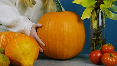 Medium plan. Autumn composition. The girl puts a pumpkin on the table. Stock Footage 210175719
