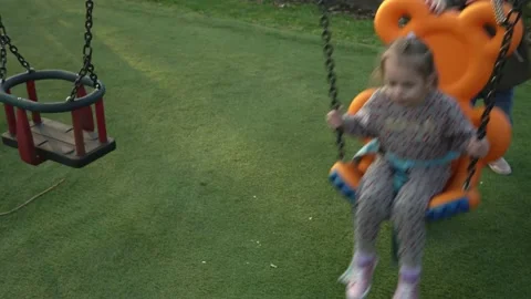 Medium Plan of Funny Little Preschool Girs In Swinging On Swing Before Sunset Stock Footage 173328686
