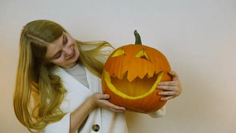 Medium plan. The girl poses for the camera with a pumpkin. Halloween. 4k. Stock Footage 219261069