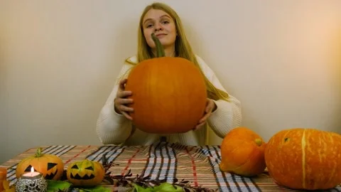 Medium plan. The girl puts a big pumpkin on the table. Stock Footage 219253539