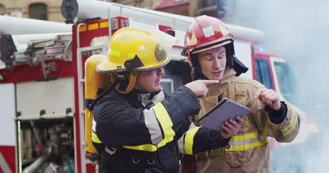 Medium plan of two firefighters discussing rescue plan looking at tablet while Video stock 137893710