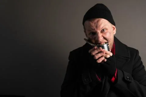 Medium plan young homeless man rejoices in a tin can. Unemployed beggar conce Stock Photos