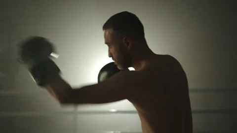Medium profile shot of middle-aged boxer performing shadow boxing in gym Stock Footage 240585067