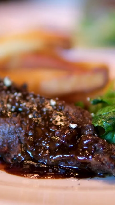 The medium rare beef steak is complemented by barbeque sauce, a fresh salad, and Vídeo Stock 295965205