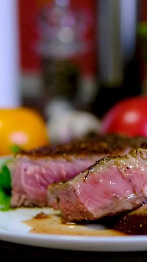 Medium rare beef steak sliced on white plate with juicy pink center served Stock Footage 346183288