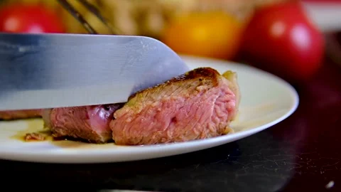 Medium rare beef steak sliced with knife revealing juicy pink center on white Stock Footage 346185394