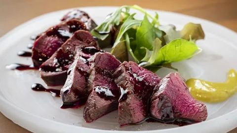 Medium-Rare Steak Slices Plated with Beets and Sauce Stock Footage 343693984