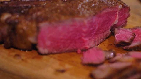 Medium rare tomahawk steak half sliced on wooden chopping board 2 Stock Footage 244704380
