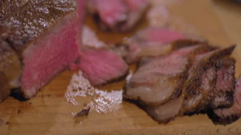 Medium rare tomahawk steak half sliced on wooden chopping board Stock Footage 244704382