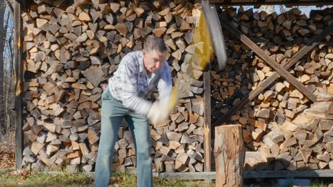 Medium Scene of a Healthy Older Man Chopping Firewood in 4K Stock Footage 85872777