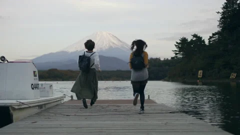 Medium shot on 4k RED camera. Excited Japanese women running up a dock on the wa Stock Footage 199459787