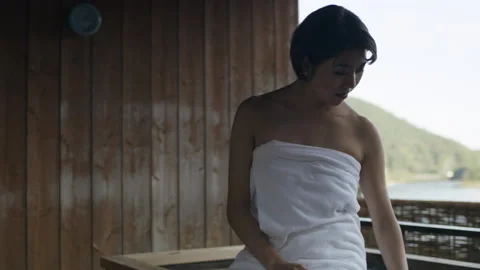 Medium shot on 4k RED camera. Relaxed Japanese Woman sitting on edge of hot wate Stock Footage 199460800