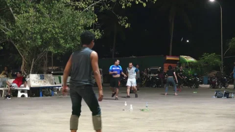Medium Shot of Asian Men Playing Hacky Sack at Night Stock Footage 130849392