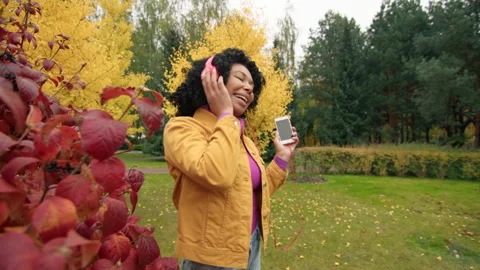 Medium shot of attractive Afro-American dancing to the cheerful melody in phone Stock Footage 254284645