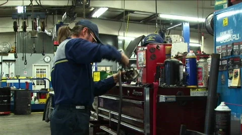 Medium-shot of an auto mechanic working in a garage Stock Footage