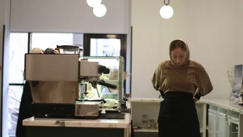 Medium shot of barista puts on an apron near the coffee machine Stock Footage 232203600