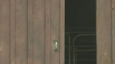 Medium shot of a barn door with empty animal pen visible behind it Video stock 202897422