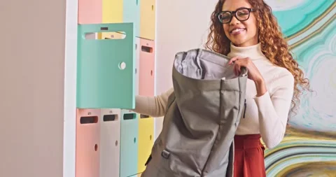 Medium shot of biracial student packing her books into backpack, campus locker Stock Footage 244535491