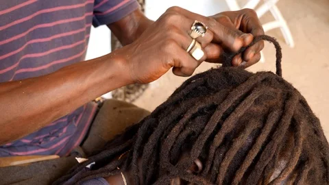 Medium shot of black hands tiddying dreadlocks at the base while smoking Stock Footage 116277783