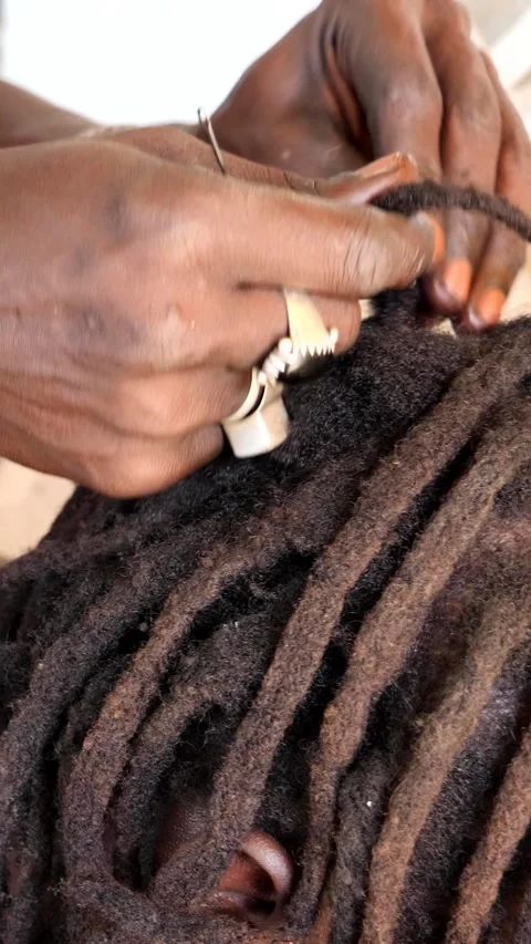 Medium shot of black hands tiddying dreadlocks at the base while smoking Stock Footage 230667849