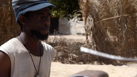 Medium shot of black man head with hat playing dundun with wooden sticks Video stock 113166587