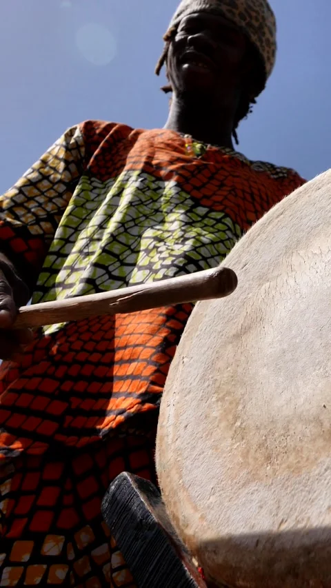 Medium shot of black man hitting skin of dundun with wooden stick Stock-Footage 228843039