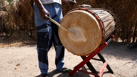 Medium shot of black man playing dundun and hitting metal stick on bell Video stock 113166605