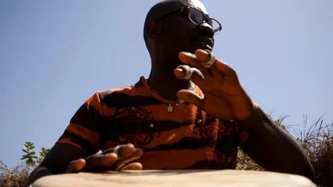Medium shot of black man playing djembe with plaster on finger Video stock 113168324