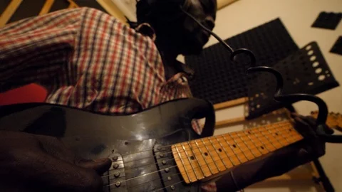 Medium shot of black man playing electric guitar sitting on chair in recording Video stock 116243276