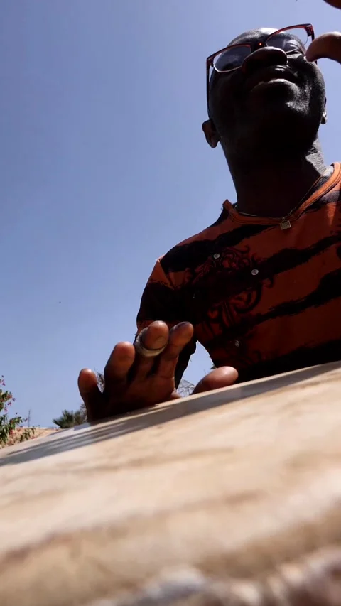 Medium shot of black man playing djembe with plaster on finger Stock Footage 230662886
