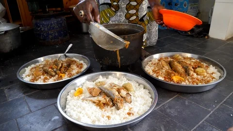 Medium shot of black woman adding sauce to 3 big bowls of rice Stock Footage 116264497