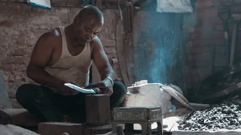 Medium shot blacksmith sharpening knife on anvil in workshop Stock Footage 166615027