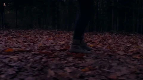 Medium shot of boots walking through fallen beech leaves in dark forest Stock Footage 134878893
