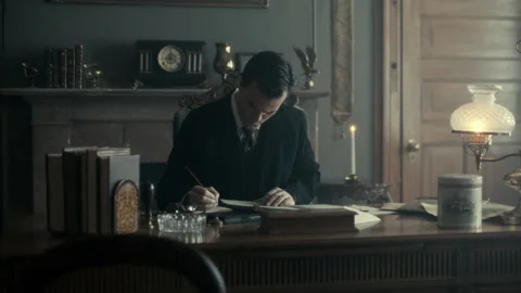 Medium shot of a businessman looking over accounts at his desk, USA, 1900s - Ree Stock Footage 236631986