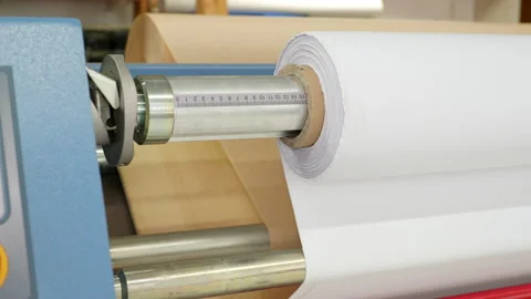 Medium shot of a calender turning a white roll of fabric.  In the background you Stock Footage 163077415