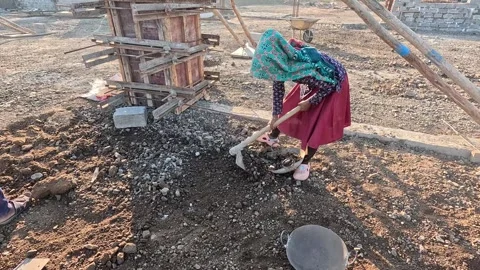 Medium shot capturing a focused female manual builder balancing a long handled Stock Footage 337869559