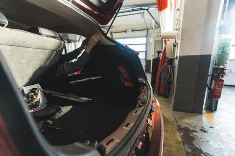 Medium shot of a car with an open trunk in a repair shop Stock Photos