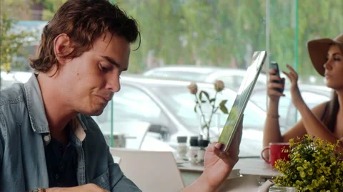 Medium shot of casually dressed man using touch screen tablet computer in cafe. Video stock 199635040