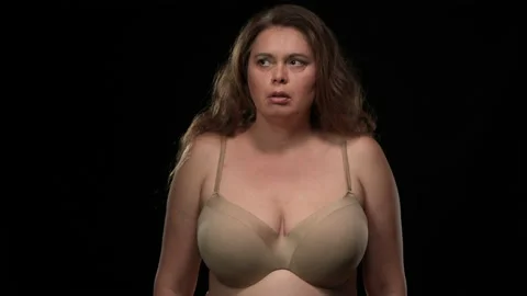 Medium shot Caucasian plus size woman in bra looking around with scared facial Stock Footage 167603121