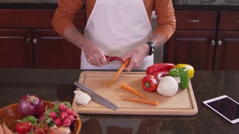 Medium shot of a chef peeling a carrot on a cutting board in a kitchen Stockbeeldmateriaal 83026638