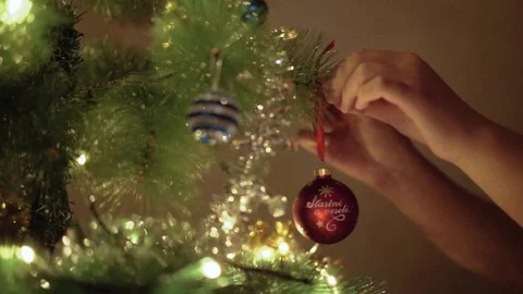 Medium shot of child decorating Christmas tree with lights. Hand hanging globe Stock Footage 81660284