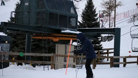 Medium Shot of Cold Ski Lift on Snow-Covered Hill With Skier in the Foreground Stock Footage 148705557