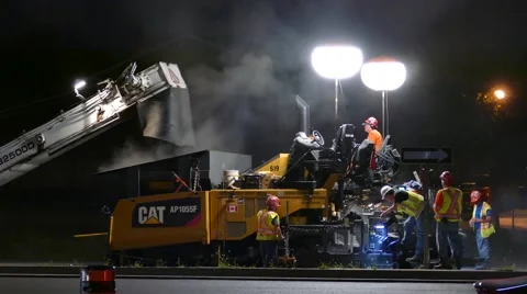 Medium shot of construction crews paving road at night Stock Footage