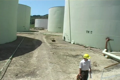 Medium shot of  contractor walking near industrial storage tanks at construction Stock Footage 438064