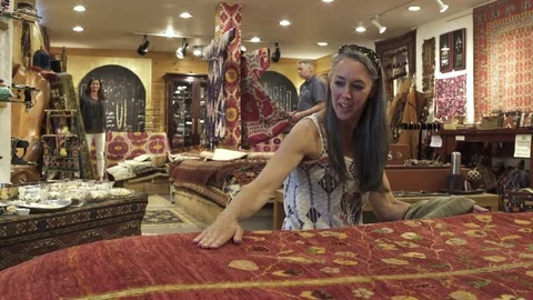Medium shot of a couple looking at carpets in a shop 動画素材 76534081