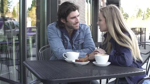 Medium shot of a couple sitting in front of a coffee shop Stock-Footage 76538938