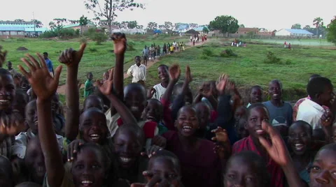 Medium shot of a crowd of children at a refugee camp Uganda, Africa, waving Stock Footage