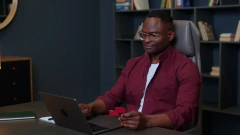 Medium shot of a dark-skinned young man working online from home, he types on a Stock Footage 262626885