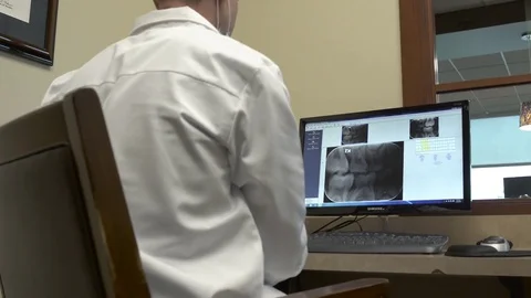 Medium shot of a dentist looking at x-rays 스톡 동영상 76217491